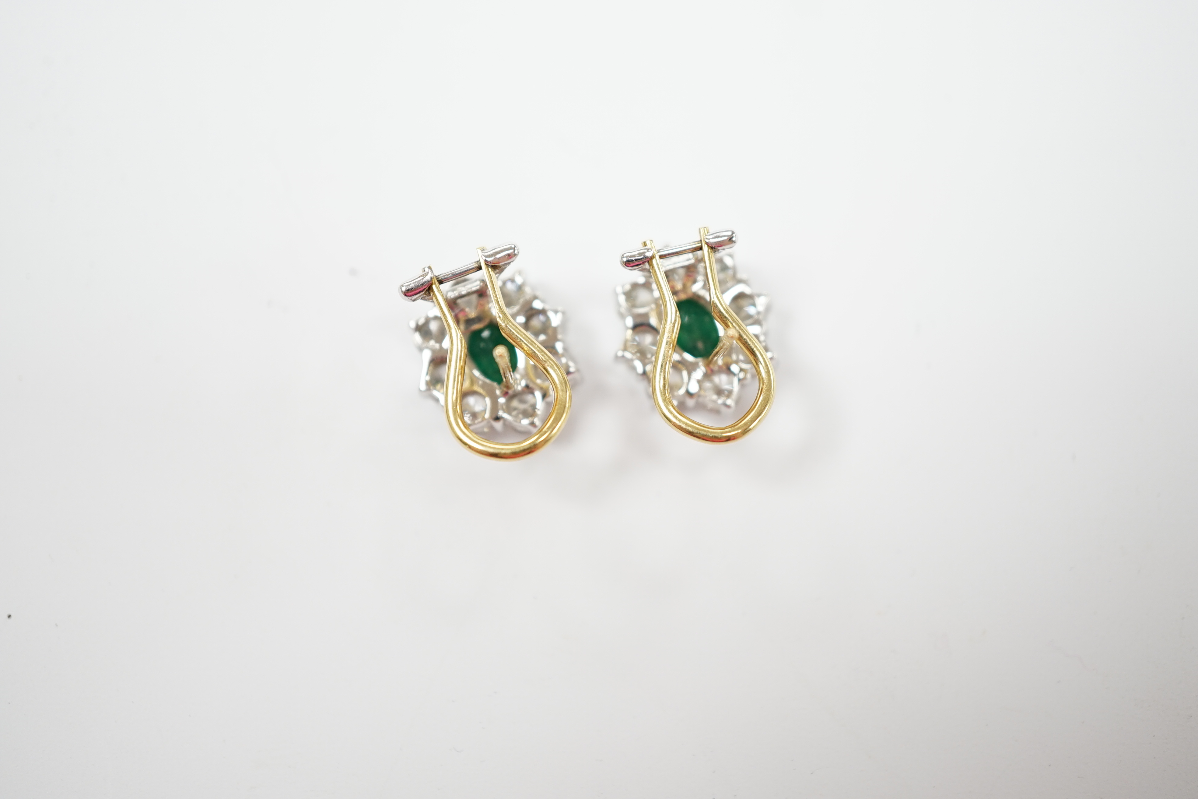 A modern pair of 18ct gold, emerald and diamond set oval cluster earrings, 13mm, gross weight 5.3 grams.